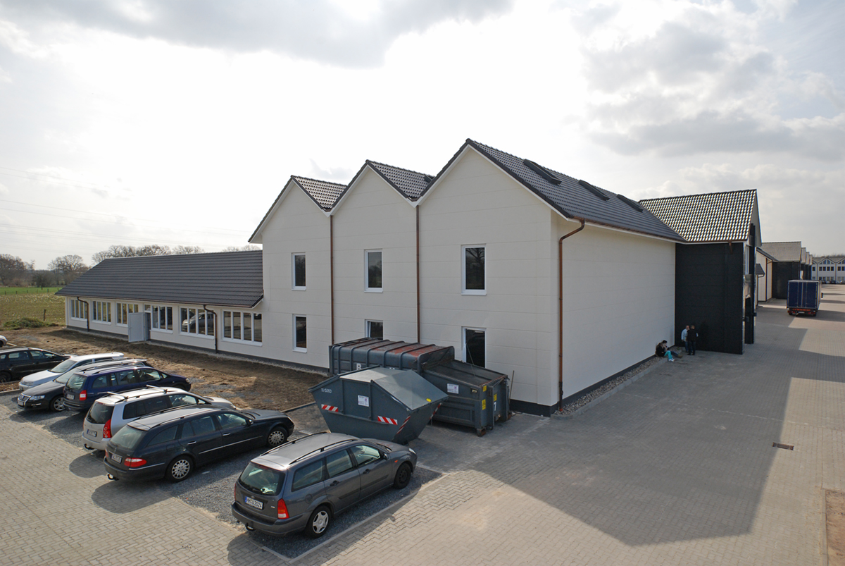 Weißer Hallenbau mit Parkplatz